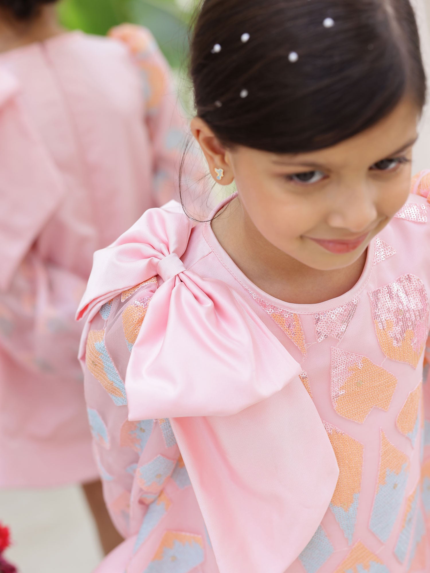 Close-up detail of the one bow on shoulder and full embellished sequin sleeve