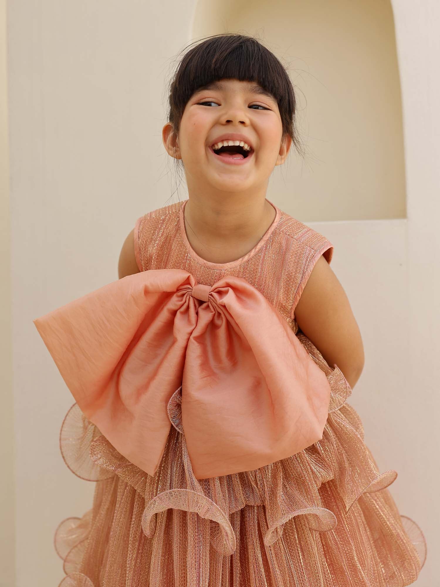 Sparkly peach-pink party dress featuring a big front bow and twirly frills.