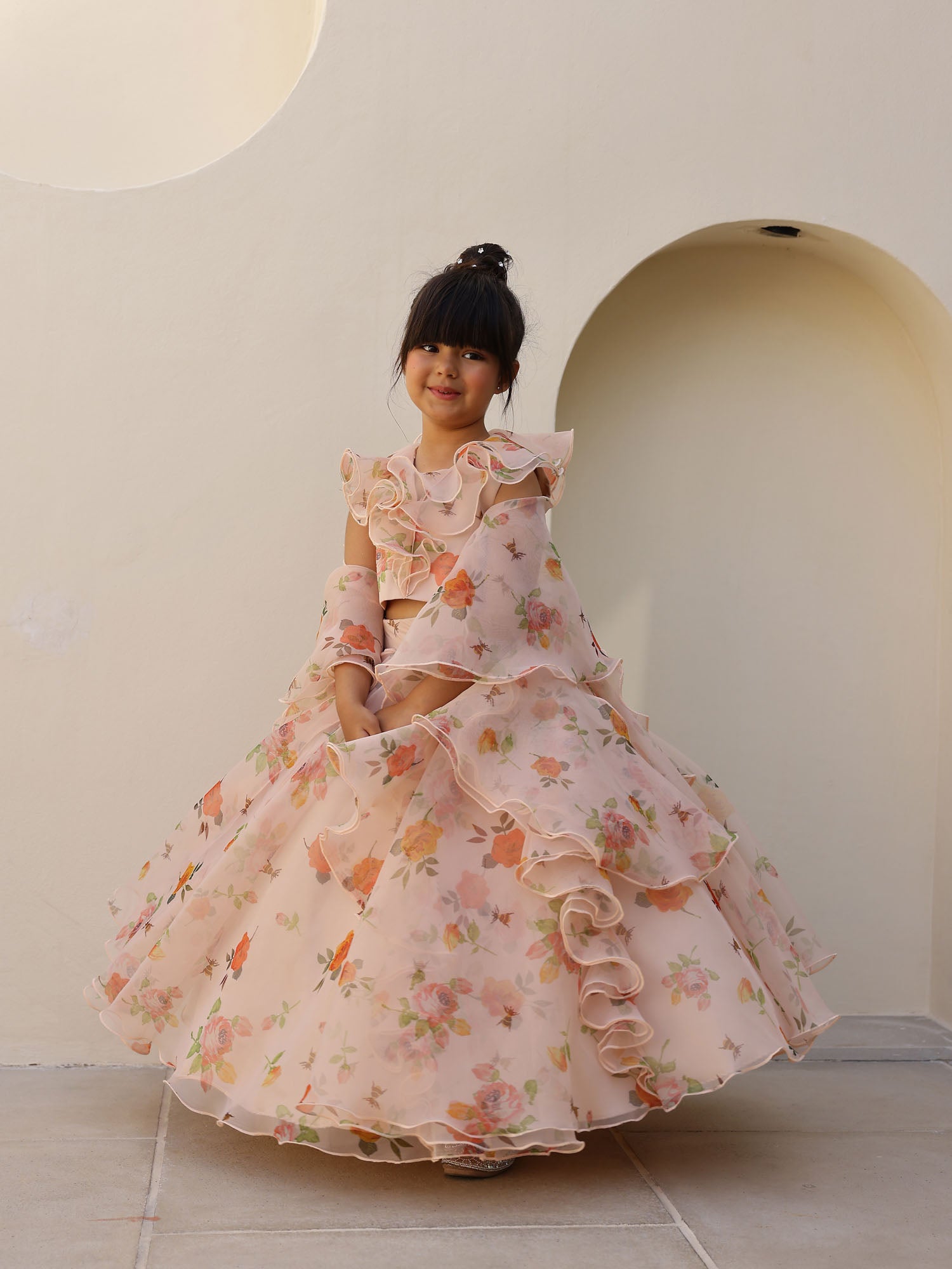 Elegant peach organza lehenga for girls with soft orange and pink flower motifs and frilled detailing.