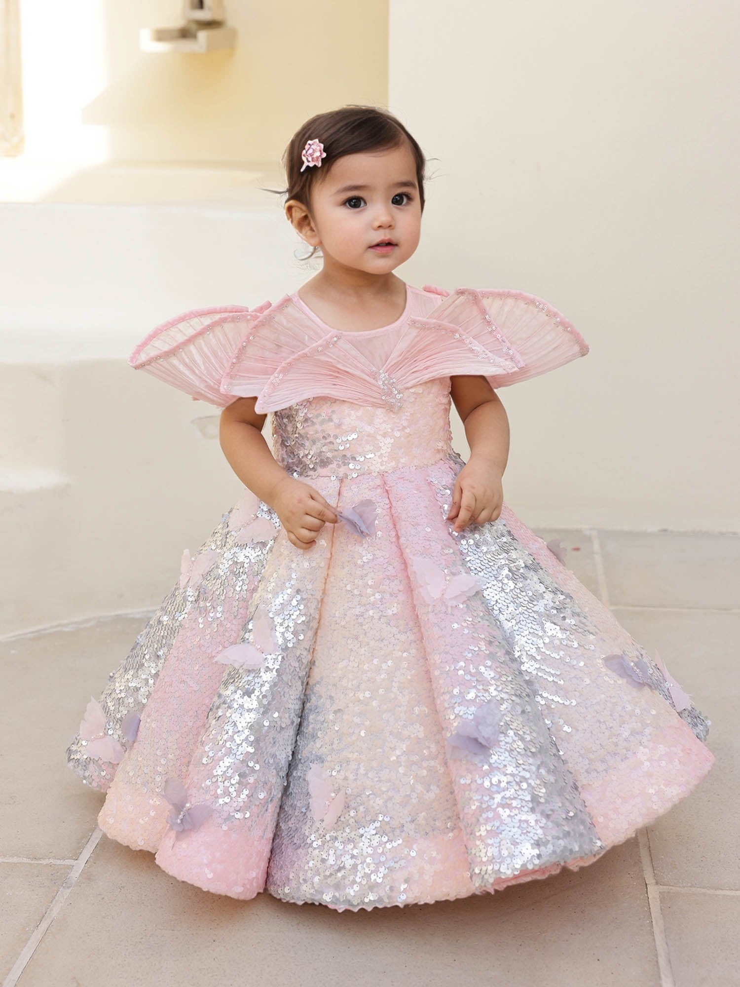 A pink shaded sequin gown with a wired neckline, pearl detailing, and butterfly accents—perfect for birthdays, carnivals, and special celebrations.