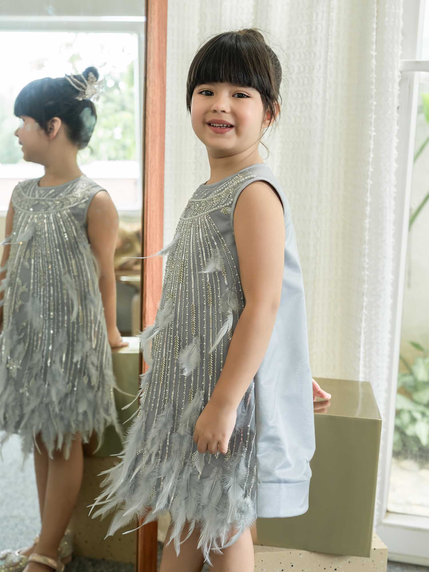 Young girl wearing a silver beaded dress with feather details