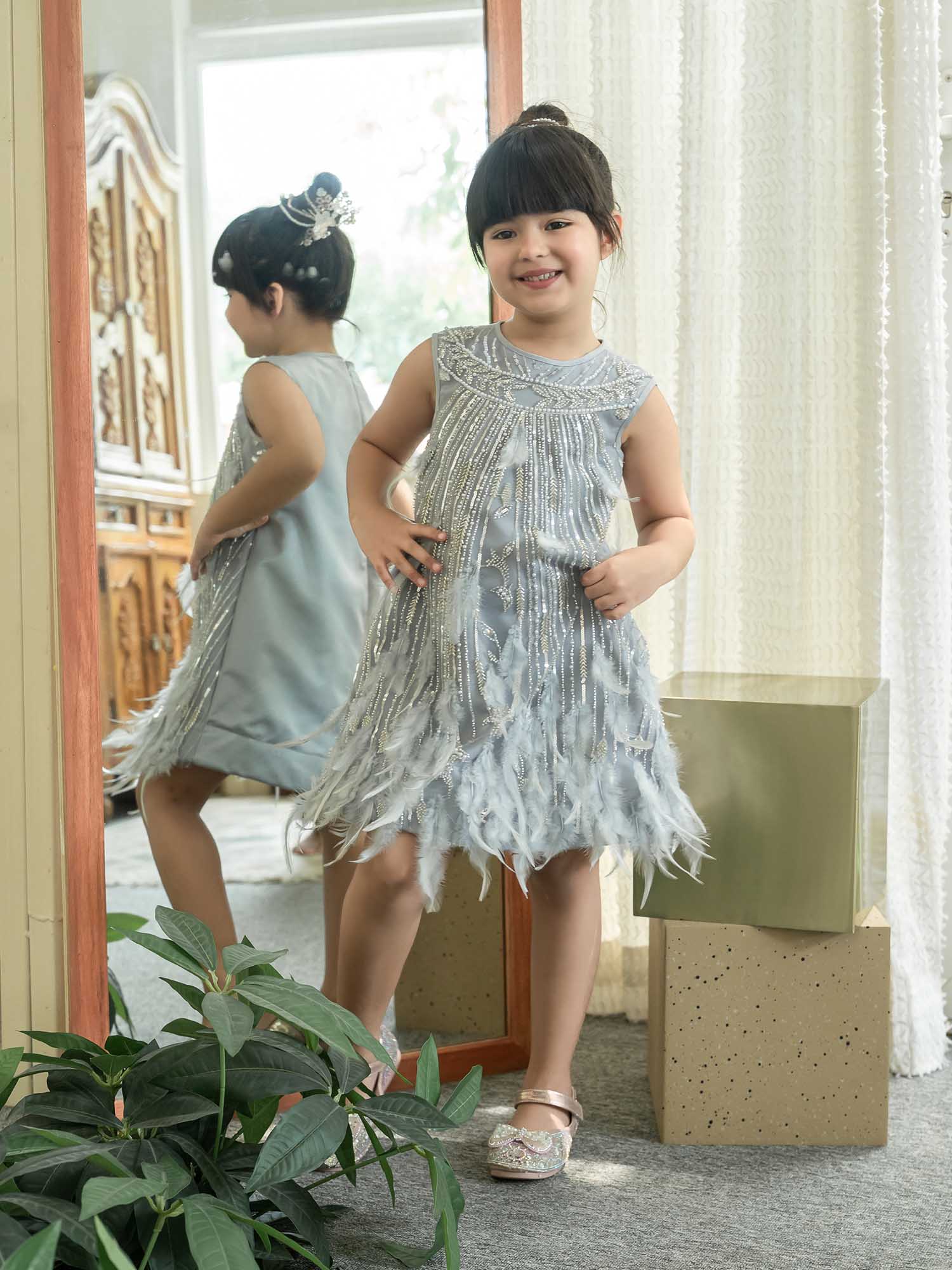 Young girl in a silver dress standing in front of a mirror