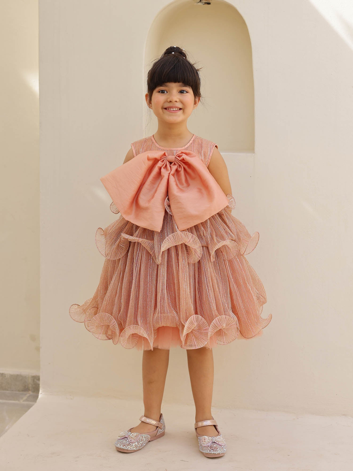 Dusty rose sparkle dress with large peach bow and ruffled tiered skirt.