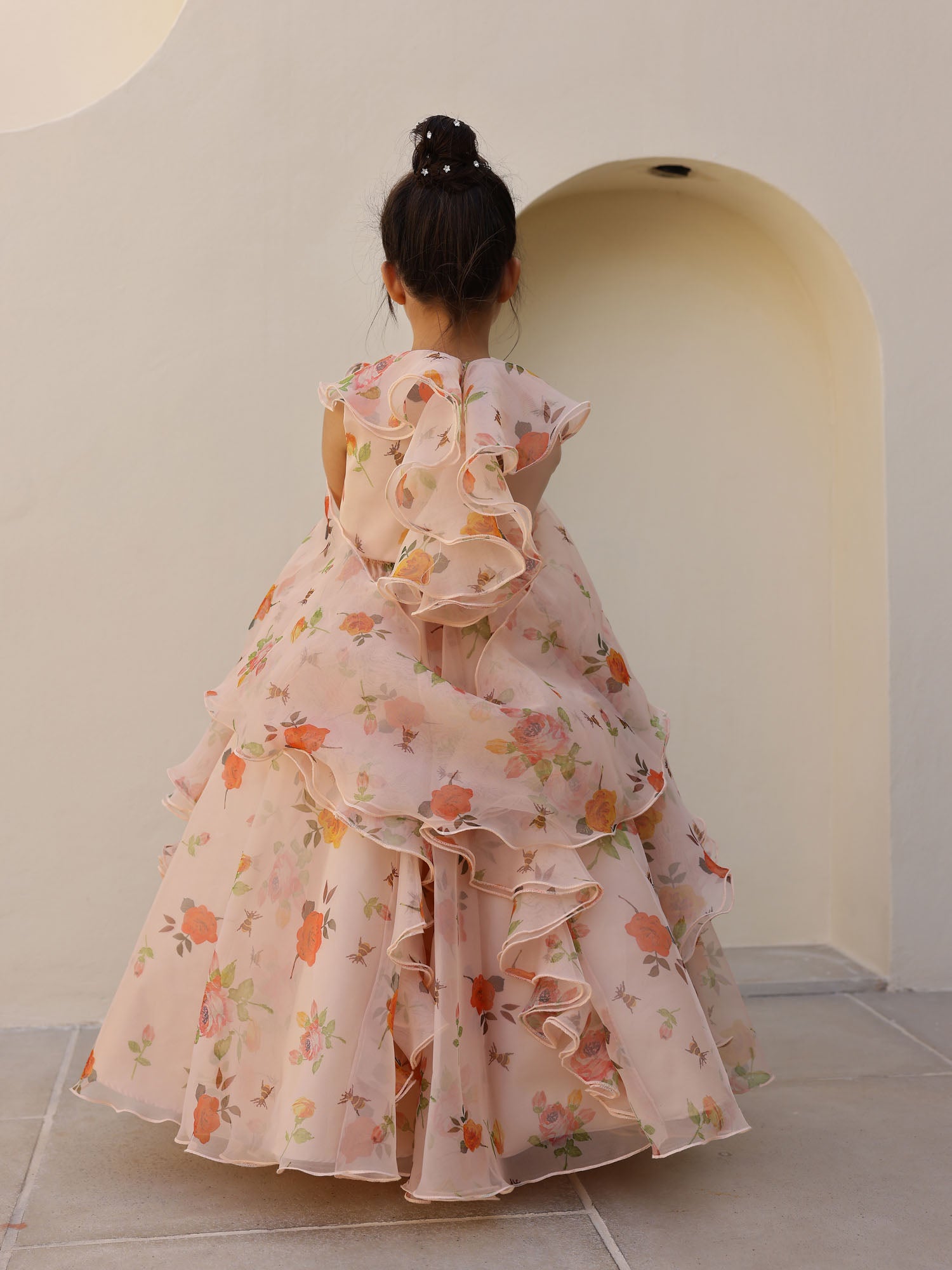 Full-length view of a girl posing in a peach floral ruffle lehenga with a stylish neckline and flowy dupatta.
