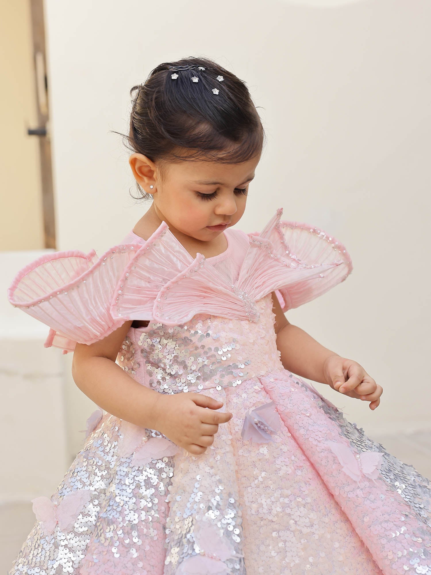 Elegant pink shimmer gown with shaded sequins, wired shoulders, and pearl accents—ideal for first birthdays and premium occasions.
